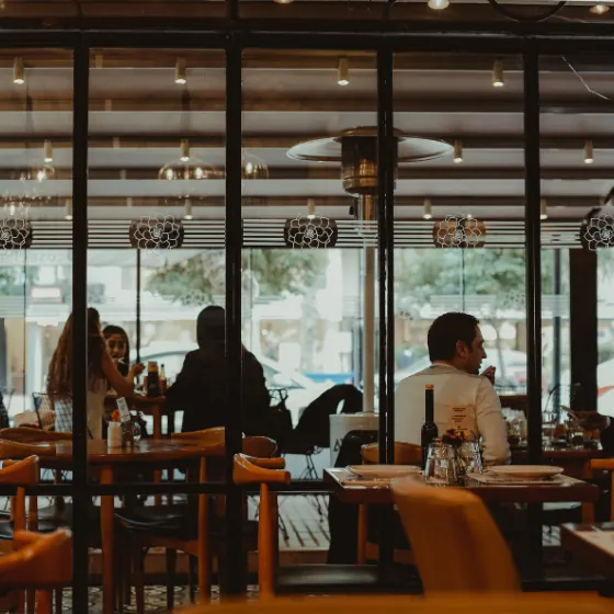 El comedor del asador de noche, con las mesas puestas y luz cálida
