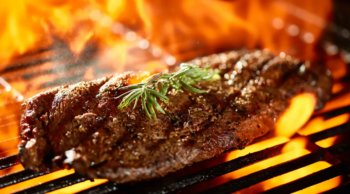 Chuletones haciéndose sobre la parrilla con las brasas encendidas debajo