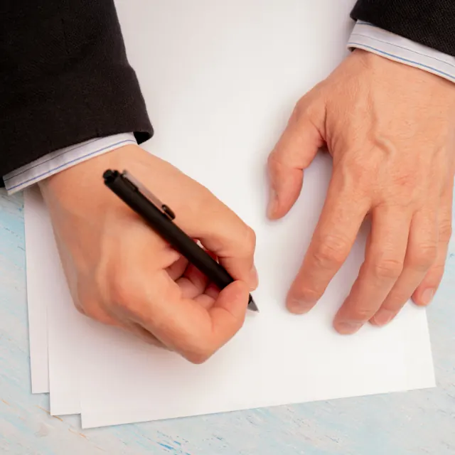 Detalle de la mesa de trabajo: un expediente abierto, anotaciones a mano y una pluma