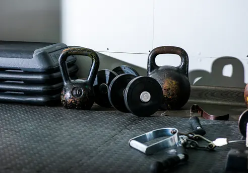 Detalle del material de la sala: kettlebells y discos ordenados en su soporte