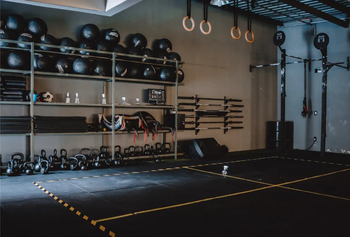 Sala de entrenamiento funcional con barras, discos y cuerdas colgadas del techo